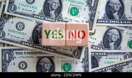 Wood cubes with words 'yes' and 'no' on beautiful background from dollar bills, copy space. Business concept. Stock Photo