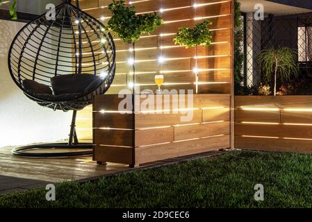 Residential Backyard Garden Wooden Recreation Place Deck with Table Illuminated by LED Outdoor Lighting. Custom Made Wooden Element. Stock Photo