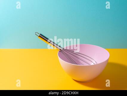 Deep bowl with a whisk on colorful background Stock Photo