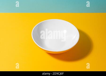 Empty deep plate on yellow and blue background Stock Photo