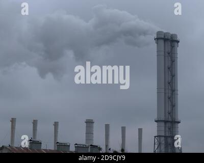 Smoke comes from industrial chimneys. The sky is covered with gray clouds. Environmental pollution. Stock Photo