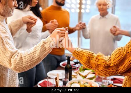 Mixed race family hands crossed other during prayer before holiday dinner Stock Photo