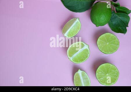 Background from a slices, whole of lime fruits with leaves on pink background. to make a drink of lemonade, tea, cocktail, mojito, detox. Stock Photo