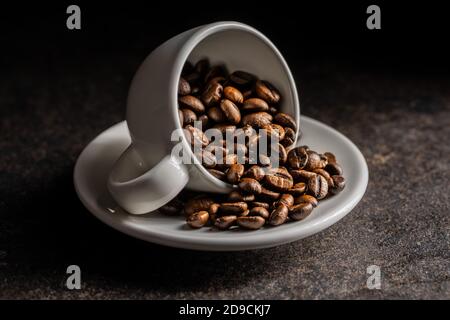 Roasted coffee beans in cup on black table. Stock Photo