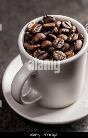 Roasted coffee beans in cup on black table. Stock Photo