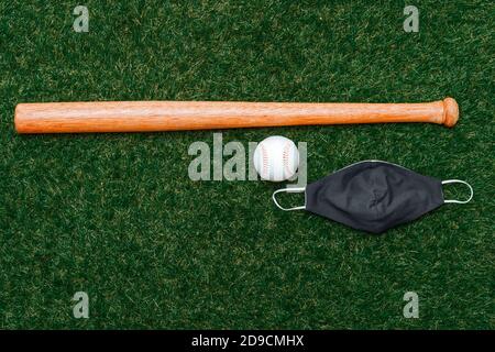 Baseball bat, ball and mask isolated on a field of grass. Baseball season with face mask. Safe sport concept Stock Photo