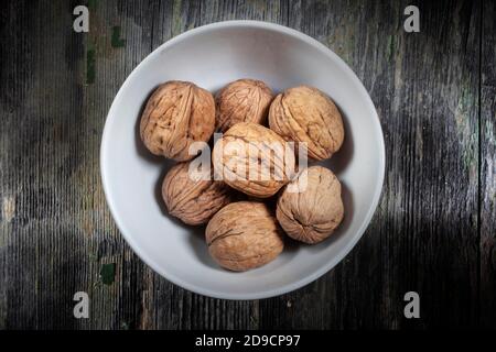 Photo From Above of Bunch of Dried Nuts in a Ceramic Bowl on Decayed Wooden Background Stock Photo