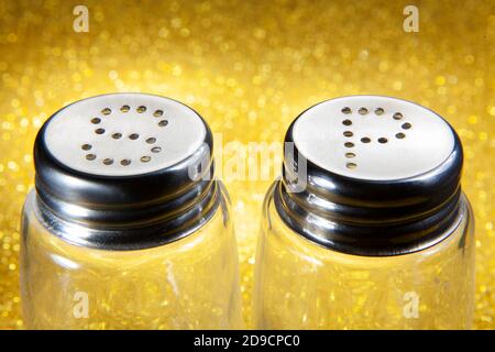 Empty Salt and Pepper Bottles on Golden Shinny Background Stock Photo