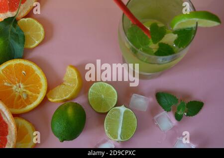 Fresh cocktail drinks with ice fruit lime and herb mint decoration. Alcoholic non-alcoholic drink-beverage. Mojito on pink background. top wiev copy Stock Photo