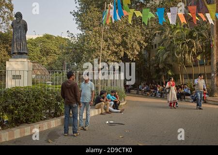 Kolkata, India, January 2016 People talking and walking in a park next to a sculpture by Rabindranath Tagore. Stock Photo