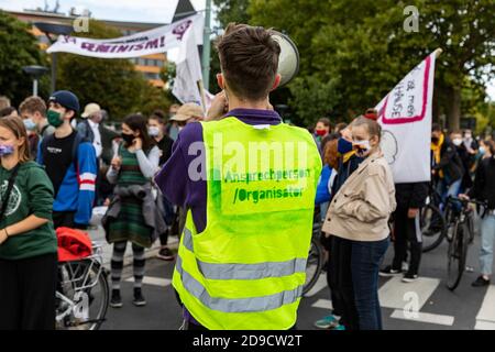 Gottingen, Germany. Autumn 2020. Fridays for future. Young man with back turned using megaphone at climate change demonstration. Stock Photo