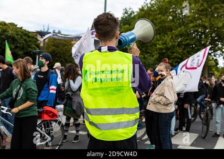 Gottingen, Germany. Autumn 2020. Fridays for future. Young man with back turned using megaphone at climate change demonstration. Stock Photo