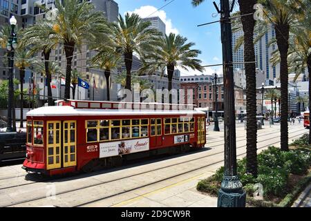 A traditional red and yellow streetcar on the Canal street line, New Orleans, Louisiana, USA. The wide street lined with palm trees & modern buildings. Stock Photo