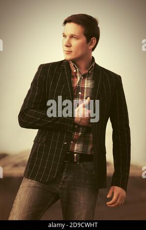 Young man in black checked blazer and shirt walking outdoor Stock Photo