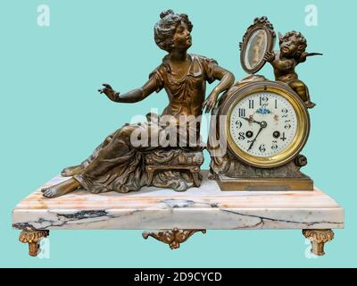 Antique mantel clock of brass woman and little angel statuettes, on isolated green background with clipping path. Stock Photo