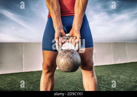 Fitness gym training man lifting heavy kettlebell weight for legs workout. Cross training class in outdoor studio Stock Photo