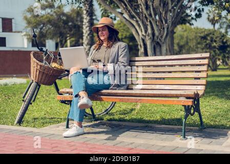 Portrait of woman working in the park wearing a hat and traveling on a bike ride Stock Photo