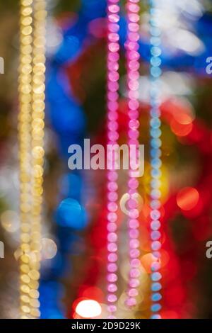 Colorful Christmas ornament decorations. Defocused abstract blurry bokeh background of balls, beads and tinsel. Out of focus glowing lights Stock Photo