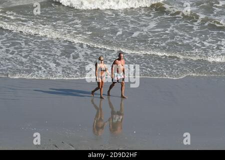Older couple walking on the beach holding hands Stock Photo