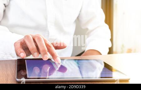 Close-up of a hand sailing on a tablet with an unrecognizable person whose face is not visible. Selective focus Stock Photo