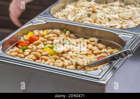 Fresh white beans stew cooking steaming in large wok pan during hotel brunch buffet outside outdoor Catering Dining Eating Party Sharing Concept Stock Photo