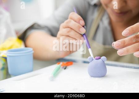 Close up of woman's hands working with fondant to decorate a cake - woman painting clay with paintbrush and dyes - woman craftswoman - clay molding to Stock Photo