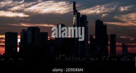 Dark skyline of a big city with skyscrapers in front of a dramatic sky with veil clouds at sunset Stock Photo