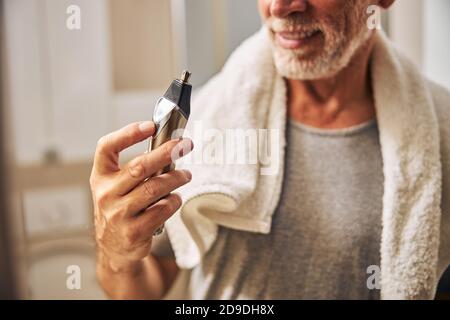 Aged man with a hair trimmer standing in the bathroom Stock Photo