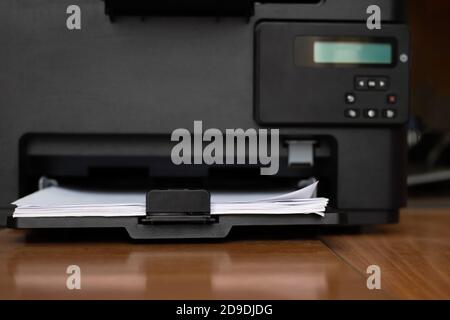 Workspace with a printer with blank sheets of paper on a wooden table, selective focus, copy space Stock Photo