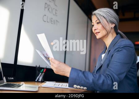 Beautiful woman studying architectural plans and using laptop at work Stock Photo