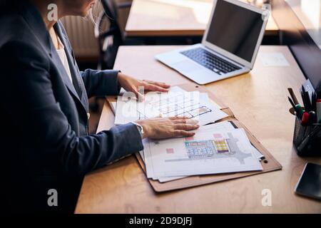 Female architect sitting at the table with laptop and papers Stock Photo