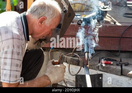 The concept of arc welding with protective metal. A man in a protective mask is engaged in arc welding of fixed iron Stock Photo