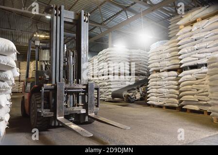 A forklift stands in a warehouse next to pallets with full bags Stock Photo