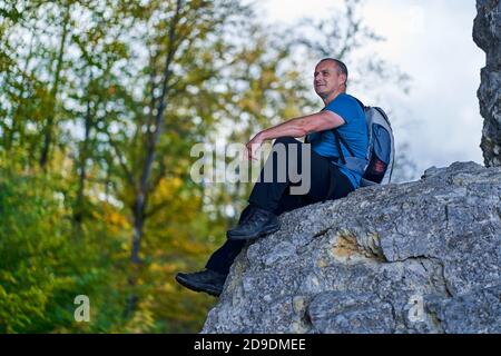 Hiker with backpack on the edge of a cliff in the mountains Stock Photo