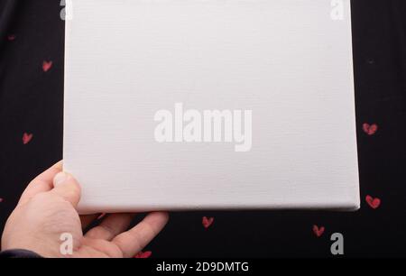 White blank canvas on black background with red hearts Stock Photo