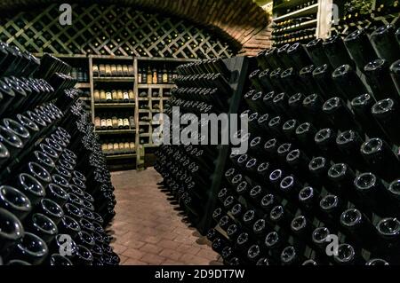 Wine cellar with wine bottles. Old wine bottles covered with dust and cobwebs are in the wine cellar of winery. Alcohol drink vintage storage Stock Photo