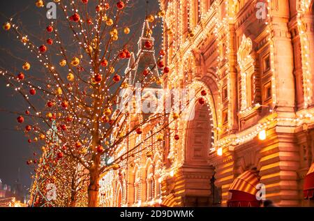 Illuminated GUM facade and New year festive decorations on Red Square, main landmark in Moscow. Christmas fair in Russia at evening while snow falling Stock Photo