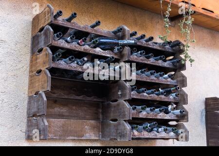 Shelf full of empty bottles of wine hanging on a wall of a building Stock Photo