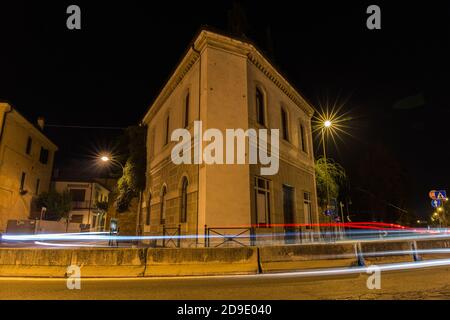 Triangular shaped building with road in front of it and car lights at night Treviso Italy Stock Photo