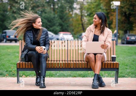 Two women chatting on bench with social distancing Stock Photo