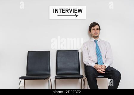 One man is sitting on chair in waiting room and waiting for interview. Stock Photo