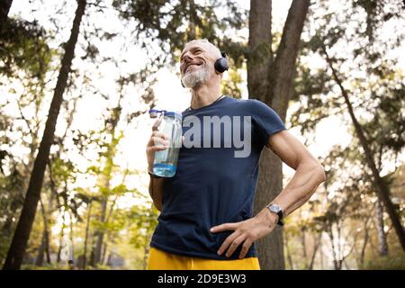 Merry athletic man going jogging in forest Stock Photo