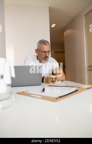 Focused male taking notes in front of a laptop Stock Photo