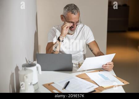 Man adjusting his glasses while checking a document Stock Photo