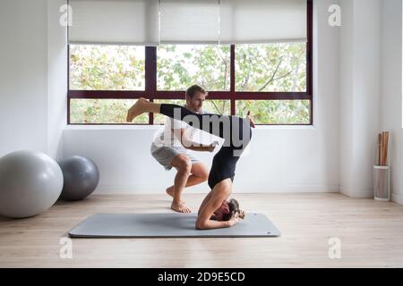 Beginner yogi and his coach practicing yoga Stock Photo
