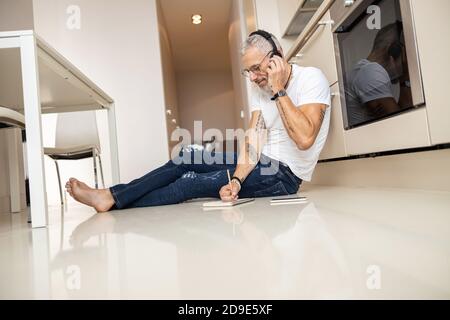 Man talking through headset and writing down in notepad Stock Photo