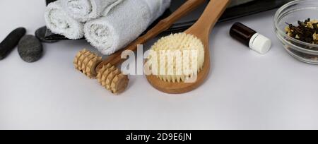 SPA Background for a banner with wellness items. Brush for dry body massage. Wooden massager for face and body. Wet white towels on a ceramic dish.  Stock Photo