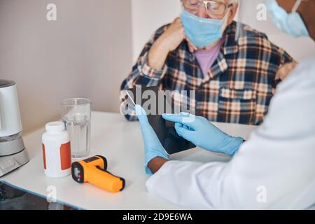 Pensioner looking at the gadget in the doctor hands Stock Photo