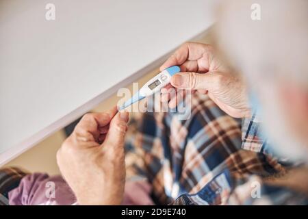 Aged man using a temperature measuring device Stock Photo