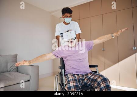 Male pensioner playing a 3D game in VR goggles Stock Photo